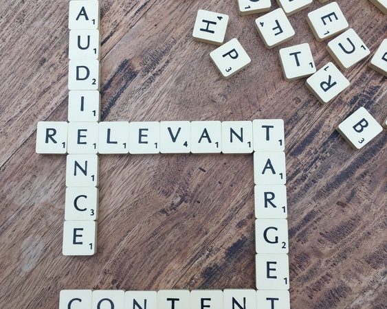 Scrabble-Buchstabensteine auf einem Holztisch bilden die englischen Begriffe AUDIENCE (Zielgruppe), RELEVANT (relevant), TARGET (Ziel) und CONTENT (Inhalt).